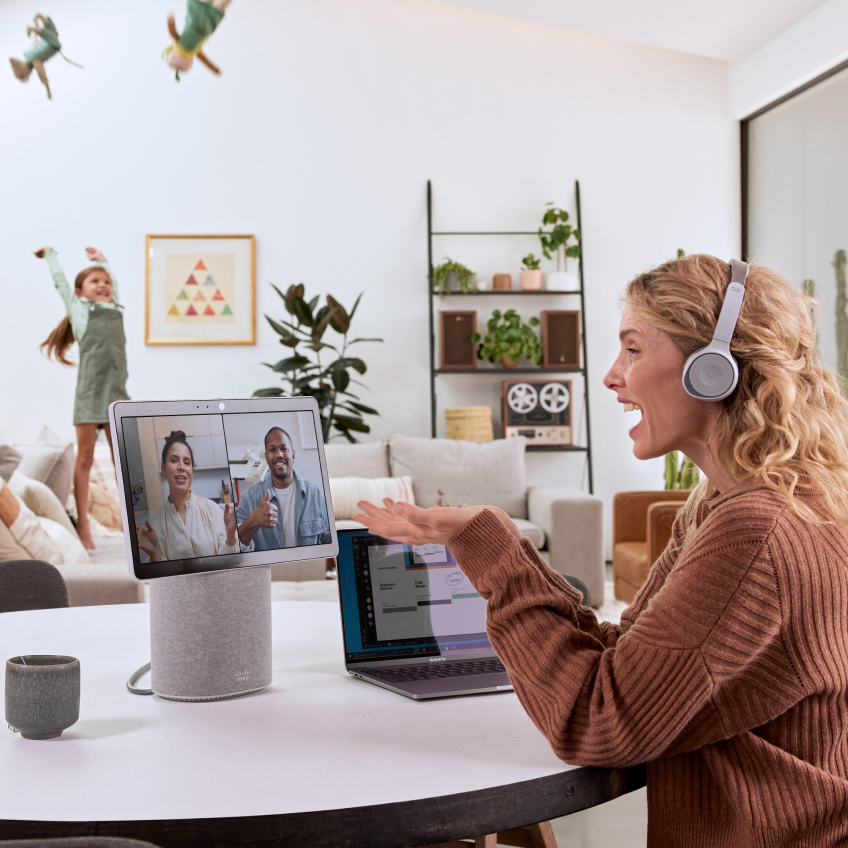 A person working from home with child using the Cisco Desk Mini and the Cisco Headset 730 - Platinum