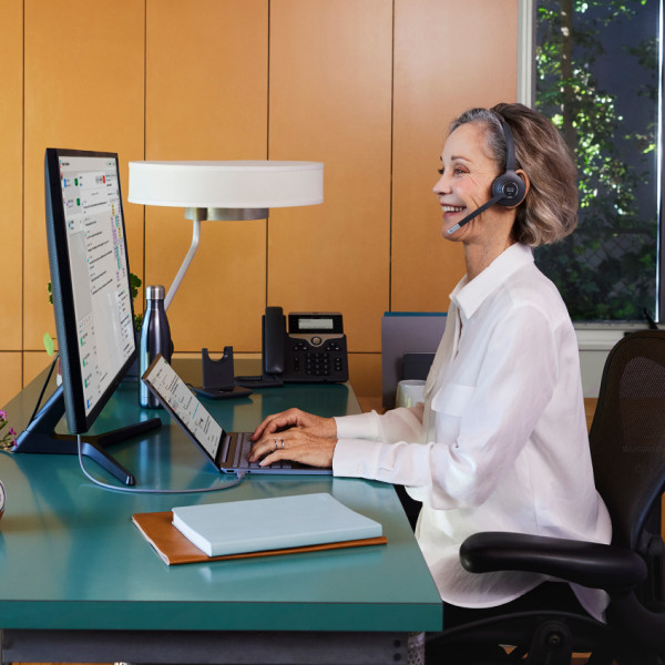 Contact center team member smiles while working at their computer in their office.