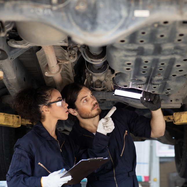 Two frontline workers examine  some machinery together.