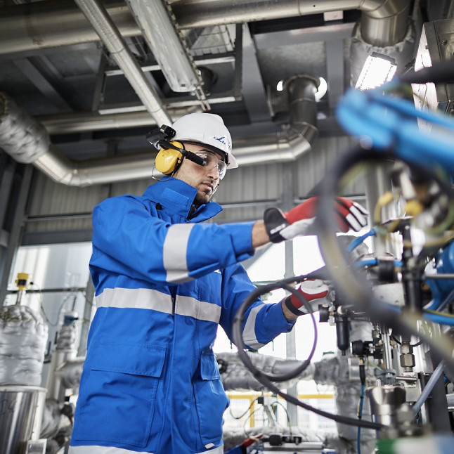 A frontline worker wearing a RealWear Headset works on some machinery.