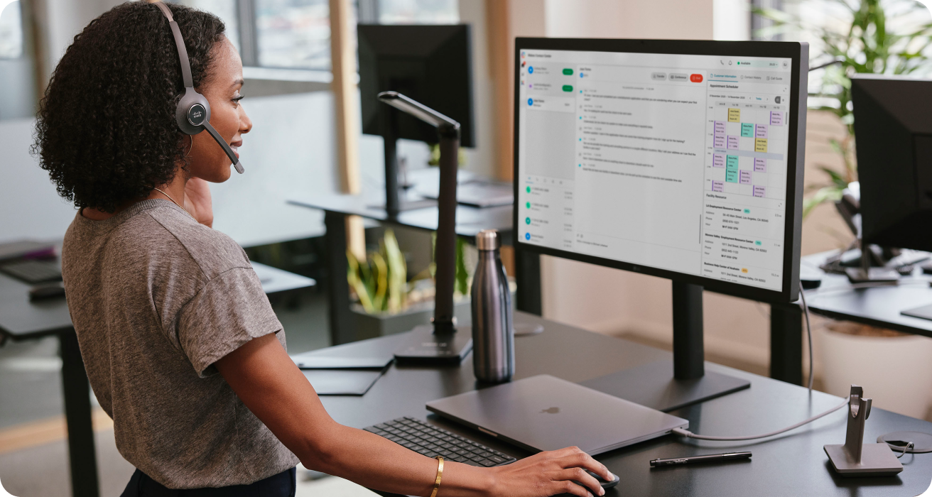 person working at a standing desk with headphones on, seemingly on a call