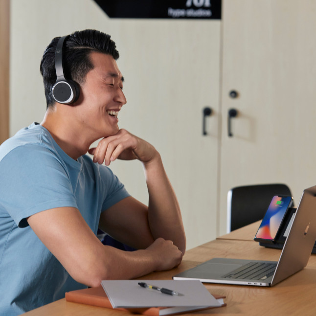 person sitting at desk with headphones on, looking casual and possibly on a call/meeting