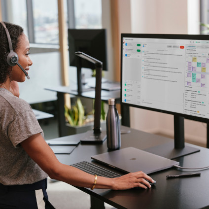 person working at standing desk with a headset on, possibly on a call