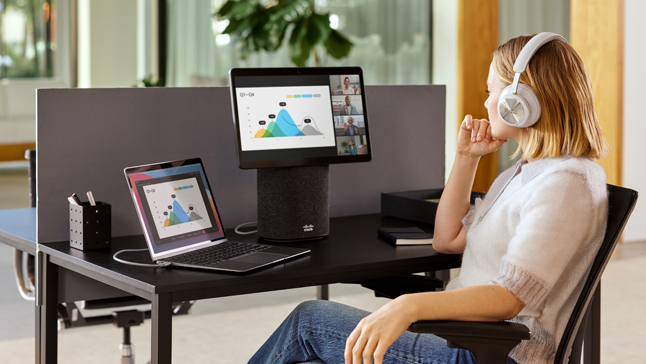 Person pauses at the reception desk in the office, looking at a screen that says Welcome and Register here.