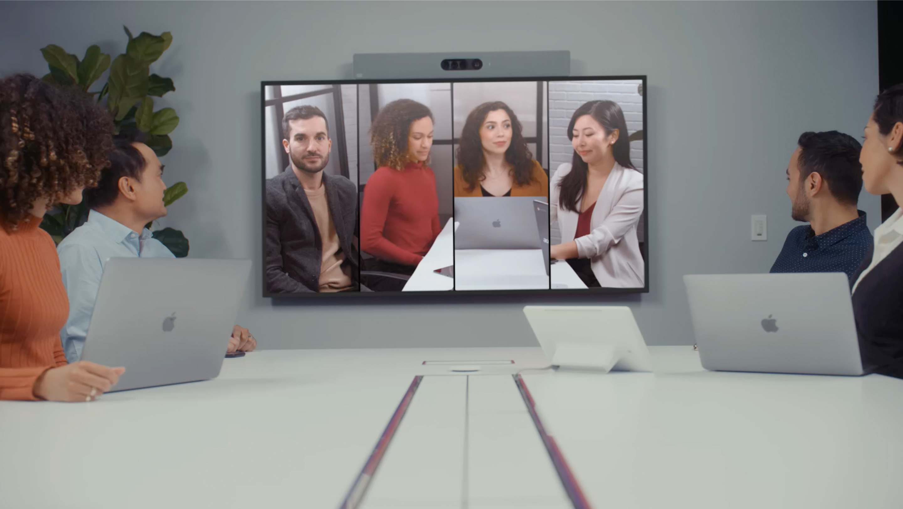 Employees in small conference room use Cisco Board Pro and Cisco Room Bar with Frames view to video conference.