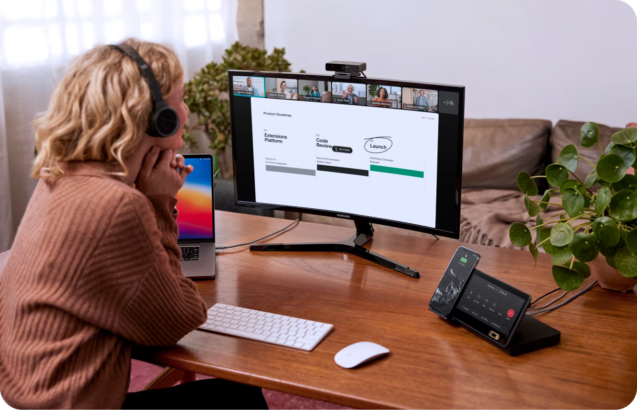 Person at a desk collaborates with colleagues via a video meeting. Someone is screen sharing, presenting a project roadmap.