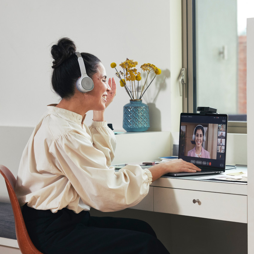 Person video conferences with colleagues from her home office via Webex Meetings on a laptop.